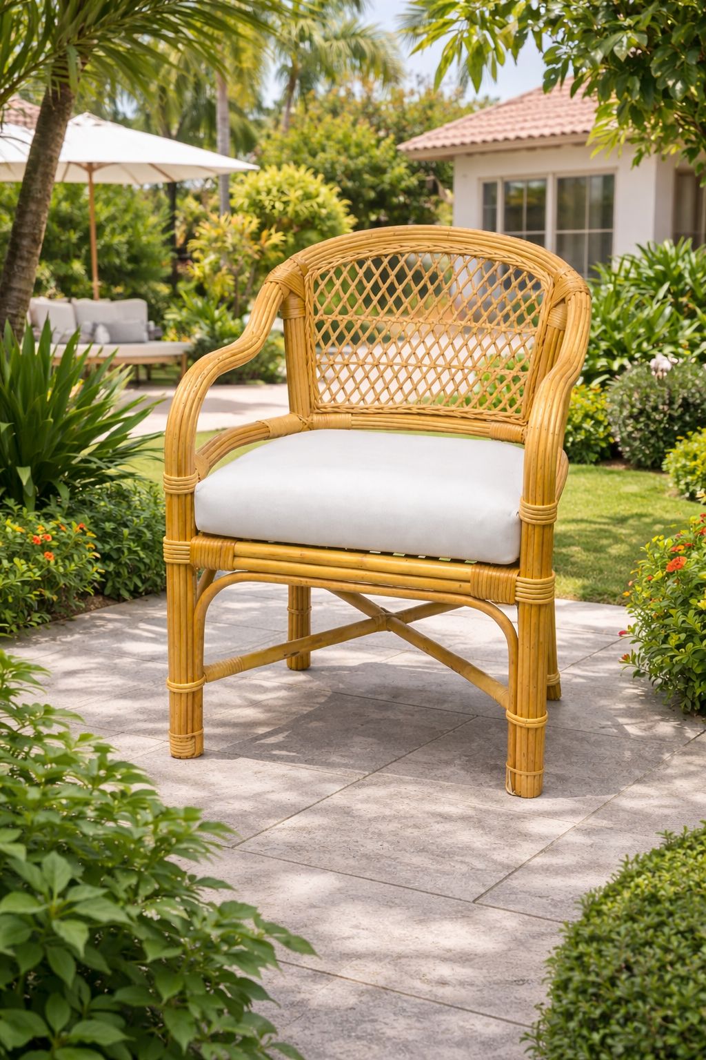 Wicker chair with a white cushion on a patio surrounded by greenery