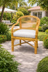 Wicker chair with a white cushion on a patio surrounded by greenery