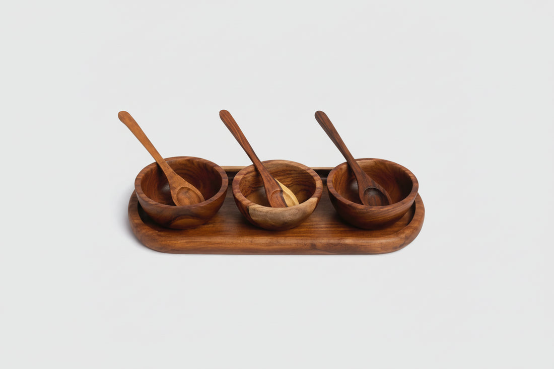 Set of three wooden bowls with spoons on a wooden tray against a white background