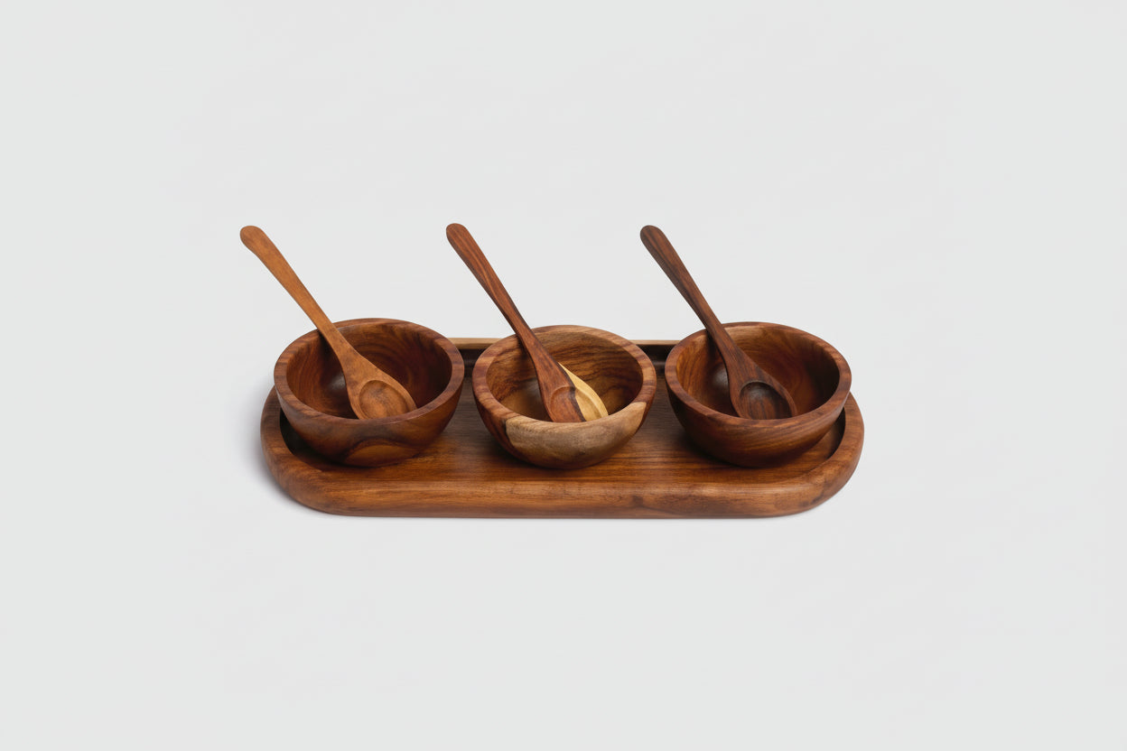 Set of three wooden bowls with spoons on a wooden tray against a white background